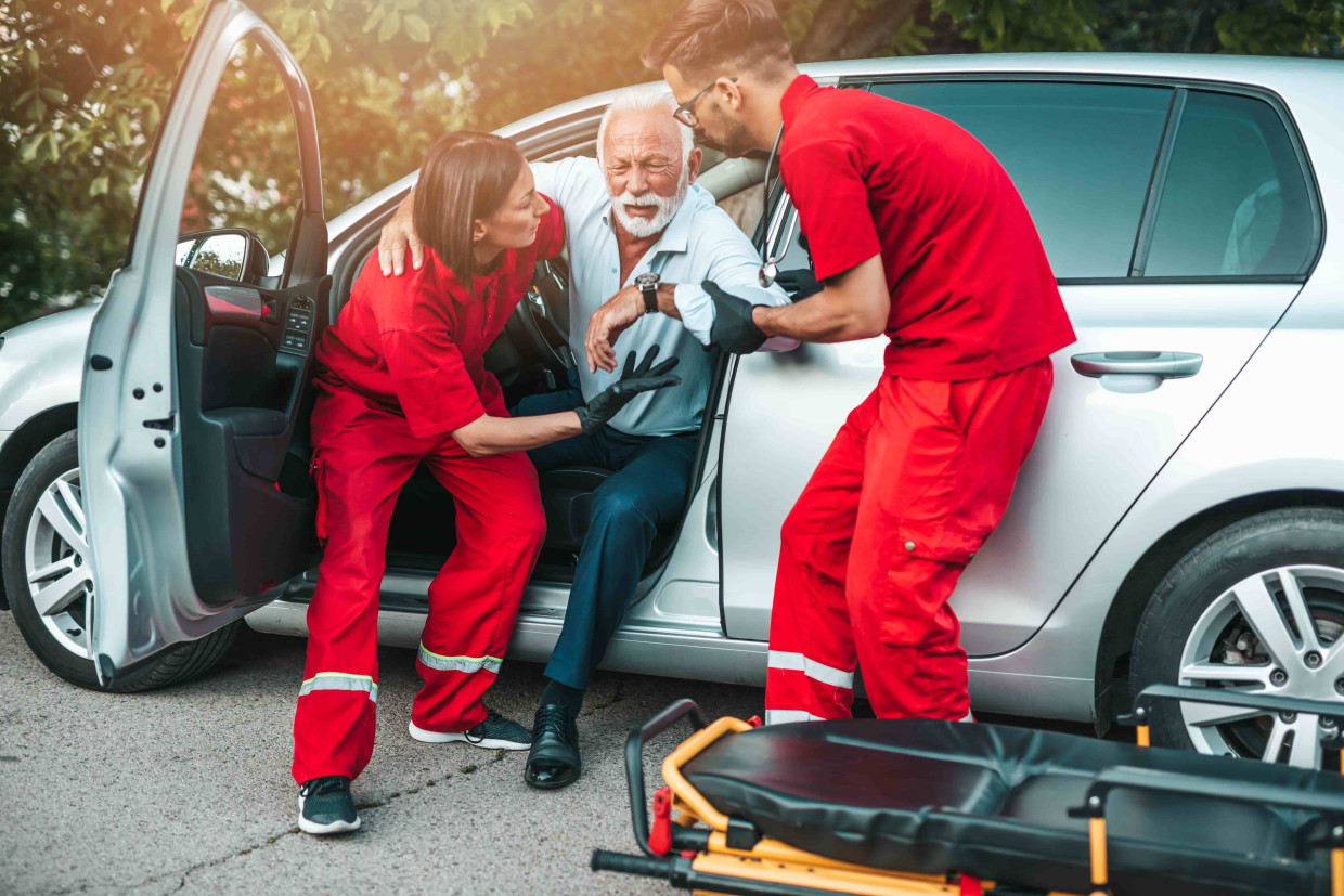 Hombre anciano saliendo del coche ayudado por un equipo médico