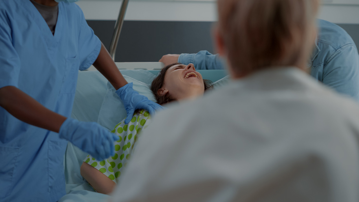 Mujer en una cama de hospital es sujetada por un enfermero