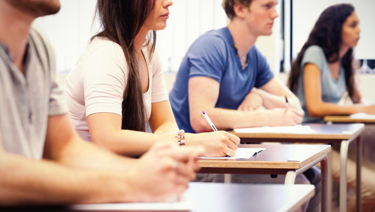 adultos jovenes estudiosos escuchando mientras están sentados escrito aula