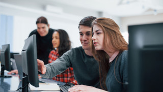 Jóvenes en clase mirando la pantalla del ordenador