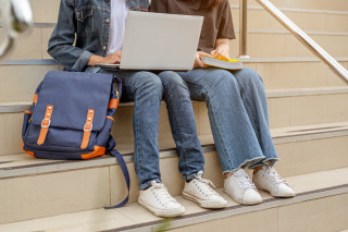 dos estudiantes sentadas en las escaleras usan computadora portátil