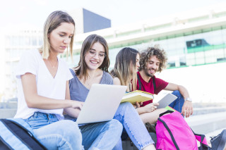 Estudiantes con ordenador portátil en la calle